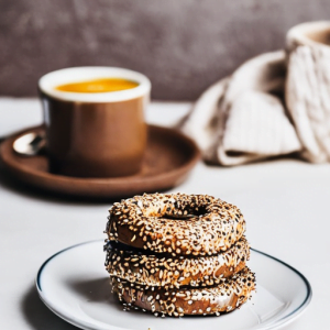 three oat bran bagels stacked on top of each other on a white plate